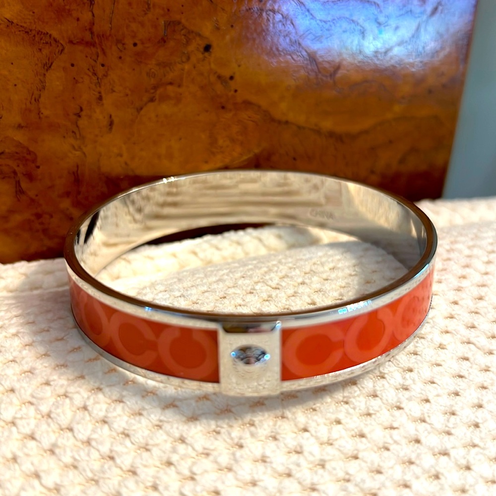 COACH: round bangle slip on bracelet. Orange and silver colors.